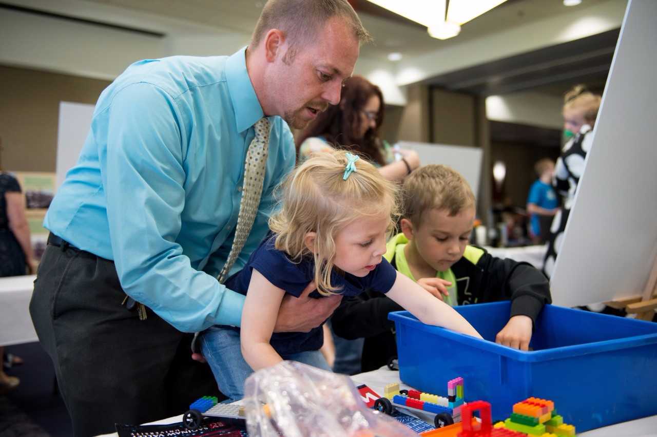 Male adult looking over the shoulder of two small children.